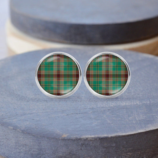 A pair of round stud earrings featuring a green Tartan pattern displayed on a grey dish.