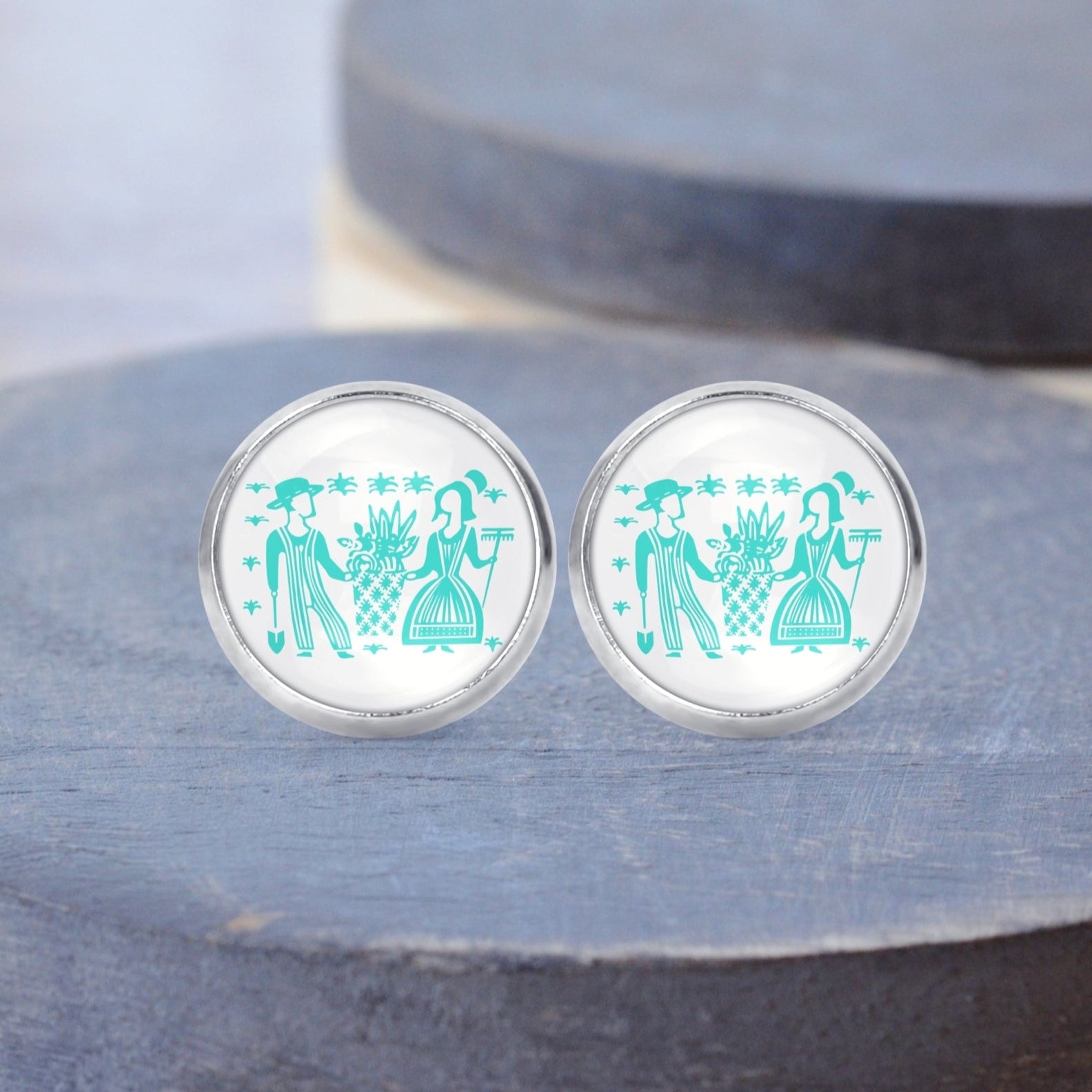 Butterprint Pyrex people printed on surgical steel stud earrings displayed on a gray wood background. 